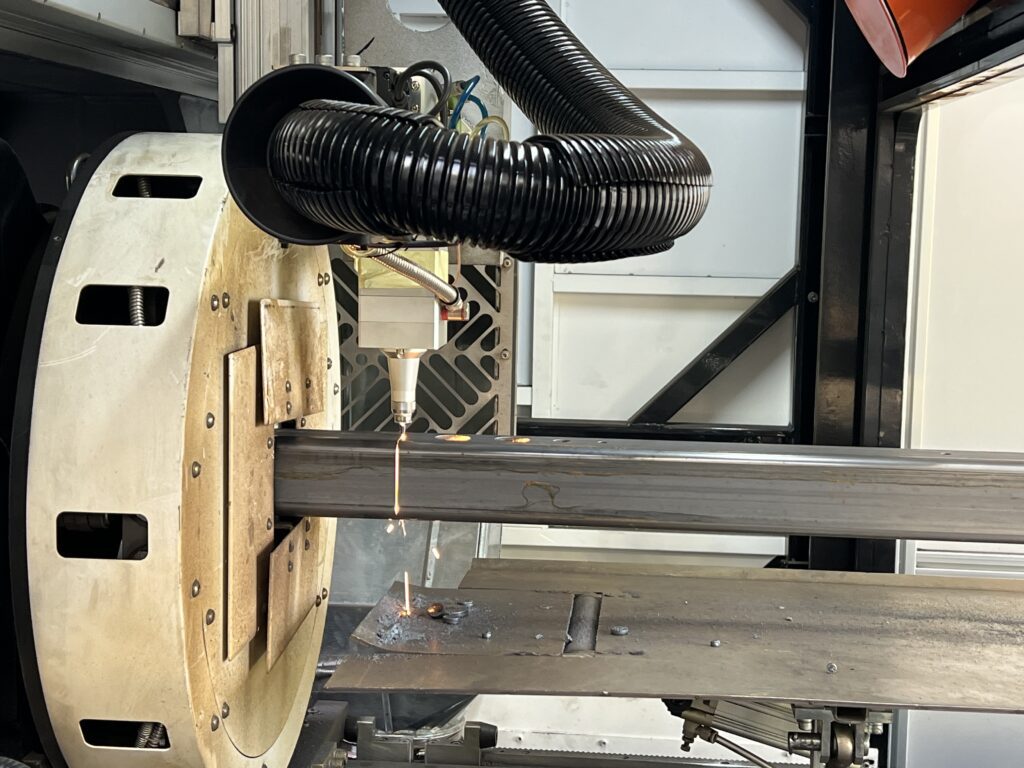 Specjalistyczna maszyna wykorzystująca cięcie laserowe do obróbki metalowej belki, tworząc otwory i cięcia.